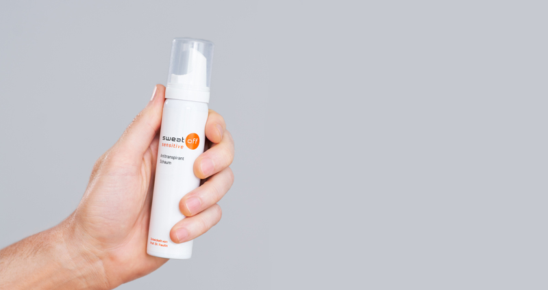 Hand hält Schaum vor grauem Hintergrund