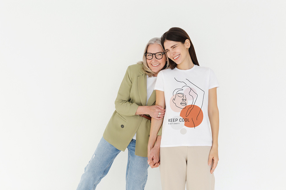 Zwei Frauen aneinander gelehnt lächeln. Rechts trägt Keep Cool Shirt