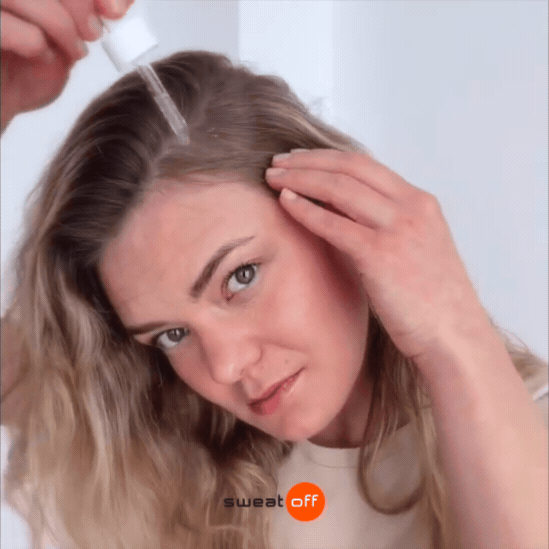 Frau mit blonden Haaren trägt am Ansatz das Serum auf