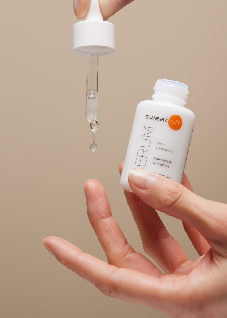 Hand hält geöffnetes Serum und Pipette zwischen den Fingern