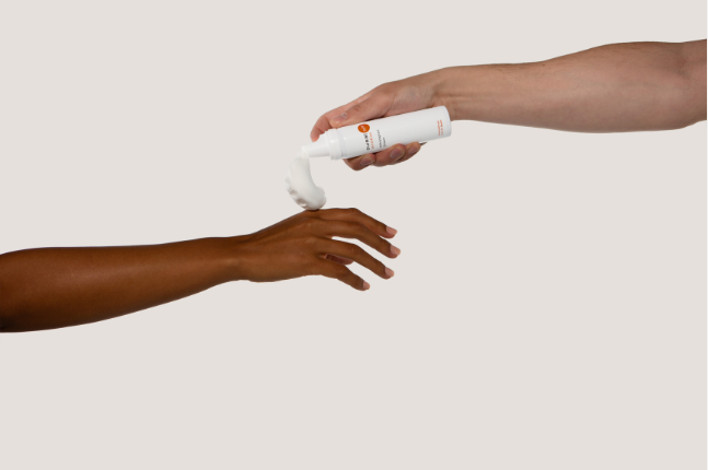 zwei Arme zu sehen, eine Hand hält den Antitranspirant Schaum und gibt der anderen Hand etwas Schaum auf die Hand