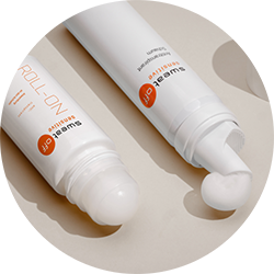 liegender Antitranspirant Roll-On geöffnet, daneben liegt der Antitranspirant Schaum geöffnet