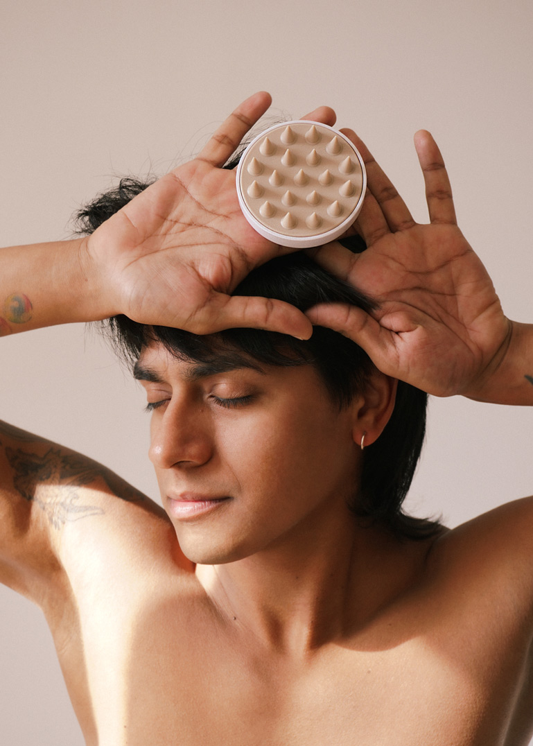 Mann mit schwarzen Haaren hält die Sweat-Off Brush an seinen Kopf.